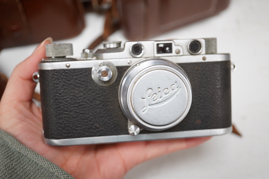 A Leica Model II camera in its original leather case, No. 204618, together with four additional cameras; a Zeiss Ikonta, a Zeiss Nettar, a Prinzflex 500E, and an Ensign Midget camera in its original card box with instruc